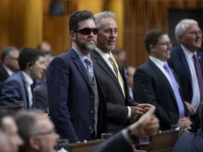 Conservative MPs Scott Reid, left, and Tom Lukiwski rise to vote during a marathon voting session as it continues into the night in the House of Commons on Parliament Hill in Ottawa on Wednesday, March 20, 2019. THE CANADIAN PRESS/Justin Tang