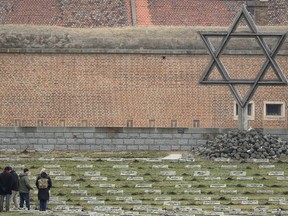 Visitors walk past the Star of David at the cemetery of the former Nazi concentration camp in Terezin, Czech Republic, Jan. 24, 2019.