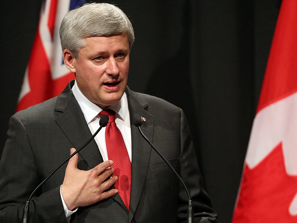 Canadian Prime Minister Stephen Harper autographs a fan's jersey