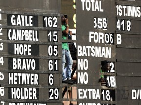 From behind the scoreboard, ground workers watch the fourth One Day International cricket match between England and West Indies at the National Stadium in St. George's, Grenada, Feb. 27, 2019. (RICARDO MAZALAN/AP files)