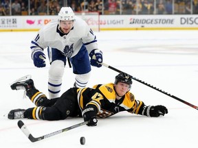 Torey Krug (bottom) of the Bruins slides on the ice ahead of Zach Hyman of the Maple Leafs reaching for the puck during the third period of Game Five of the Eastern Conference First Round during the 2019 NHL Stanley Cup Playoffs at TD Garden on April 19, 2019 in Boston. (Maddie Meyer/Getty Images)