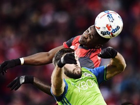 Toronto FC defender Chris Mavinga heads the ball above Seattle Sounders defender Will Bruin during a game last year. (THE CANADIAN PRESS)