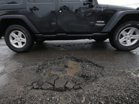 Cars try to dodge a series of potholes along O'Connor Dr. on March 13, 2019.