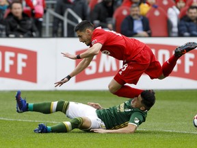 Toronto FC midfielder Marky Delgado dives over Portland Timbers defender Jorge Moreira during Saturday's game. (THE CANADIAN PRESS)