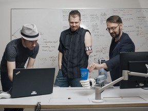 Lead Research Engineer Michale Rory Dawson, left, sets up a task for research participant Chris Neilson to perform with the Bento Arm, centre, while Patrick Pilarski, who is the Canada Research Chair in machine Intelligence for Rehabilitation, gives it a cup to hold at the University of Alberta's BLINC lab in Edmonton, Alberta, on Thursday March 14, 2019.