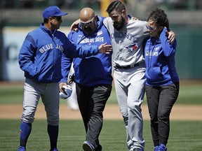 Toronto Blue Jays manager Charlie Montoyo, left, speaks with pitcher Matt Shoemaker, second from right, as Shoemaker is helped off the field after sustaining an injury during a rundown play against the Oakland Athletics in the third inning of a baseball game Saturday, April 20, 2019, in Oakland, Calif.