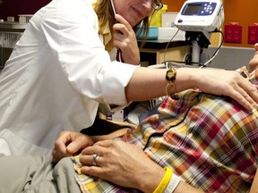 A nurse practitioner listens to  a patient's heart.
