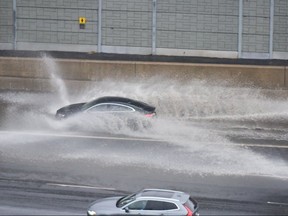 A car drives through a flooded portion of the westbound 401 near Avenue Rd. on April 26, 2019.  Heavy rain caused localizing ponding and flooding throughout the Toronto area