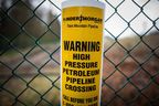 A sign warning of an underground petroleum pipeline is seen on a fence at Kinder Morgan's facility where work is being conducted in preparation for the expansion of the Trans Mountain Pipeline, in Burnaby, B.C., on April 9, 2018.