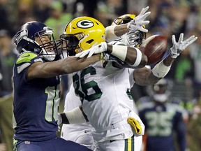 Green Bay Packers defensive back Raven Greene, center, and cornerback Jaire Alexander, right, break up a pass intended for Seattle Seahawks wide receiver Tyler Lockett during the first half of an NFL football game, Thursday, Nov. 15, 2018, in Seattle. Greene was flagged for pass interference on the play. The Seahawks won 27-24. (AP Photo/Elaine Thompson) ORG XMIT: SEA153