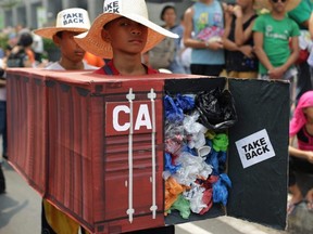 Filipino environmental activists wear mock container vans filled with garbage to symbolize the 50 containers of waste that were shipped from Canada to the Philippines in 2013, as they hold a protest outside the Canadian embassy in the financial district of Makati, south of Manila, Philippines on May 7, 2015.