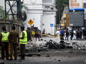 Sri Lankan security personnel inspect the debris of a car after it exploded when police tried to defuse a bomb near St. Anthony's Shrine in Colombo on Monday, April 22, 2019.