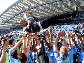 Manchester City players throw manager Pep Guardiola in the air during their title-winning celebration on Sunday. (GETTY IMAGES)