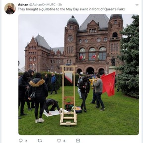 A May Day protester poses with a sign and guillotine at Queen’s Park on Wednesday, May 1 2019.
