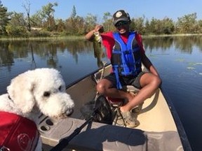 Reece Nicholson fishing with seizure response dog guide Frodo. (Supplied photo)