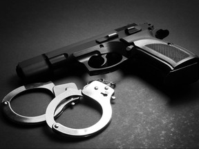 Handgun with handcuffs over dark background
