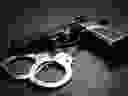 Handgun with handcuffs over dark background