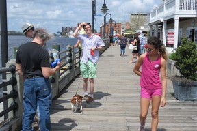 A young woman glances at a dog on the downtown Wilmington Riverwalk boardwalk beside Cape Fear River. (Ian Robertson)