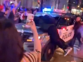 Still from a video of over-enthusiastic Raptors fans jumping on a police car on Yonge at Dundas