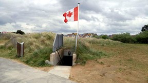 A Canadian flag blows in the breeze near the opening to one of the German-manned bunkers that defended Juno Beach in Courseulles-sur-Mer, France. (DAVE POLLARD/Postmedia Network)