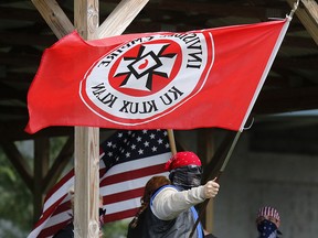 In this Sept. 1, 2018 photo, a Ku Klux Klan member waves a Klan flag during the Ku Klux Kookout where counter protests by anti-hate groups were also held at Jaycee Park in Madison, Ind. (Michelle Pemberton/The Indianapolis Star via AP)