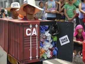In this May 7, 2015, file photo, Filipino environmental activists wear a mock container vans filled with garbage to symbolize the 50 containers of waste that were shipped from Canada to the Philippines two years ago, as they hold a protest outside the Canadian embassy at the financial district of Makati, south of Manila, Philippines.