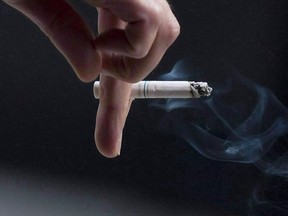 A person smokes a cigarette in downtown Ottawa on Sept. 29, 2009. Health Canada says cigarette packs will have to be plain drab brown with standardized layouts and lettering, starting in November. The government says plain packages will increase the impact of graphic health warnings about the dangers of smoking, keeping them from getting lost amid colourful designs and branding.