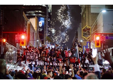 Toronto Raptors fans celebrate atop a bus after the team beat the Golden State Warriors in Game Six of the NBA Finals, on June 13, 2019 in Toronto, Canada.