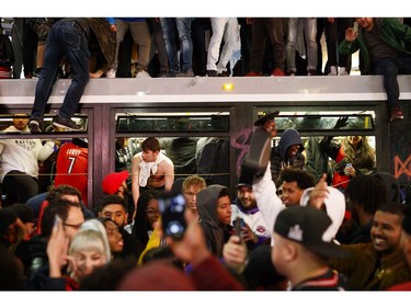 Toronto Raptors fans celebrate atop and inside a bus on Yonge St. after the team beat the Golden State Warriors in Game Six of the NBA Finals, on June 14, 2019 in Toronto.