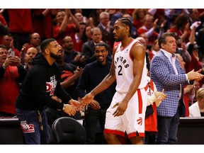 Kawhi Leonard #2 of the Toronto Raptors high fives rapper Drake during game four of the NBA Eastern Conference Finals between the Milwaukee Bucks and the Toronto Raptors at Scotiabank Arena on May 21, 2019 in Toronto, Canada.