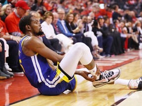Warriors forward Kevin Durant sits on the court after suffering an apparent Achilles’ tendon injury on Monday. He was to have an MRI back in Oakland yesterday.  Kyle Terada/USA TODAY Sports