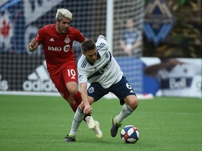 Toronto FC midfielder Alejandro Pozuelo fights for the ball with Vancouver Whitecaps midfielder Jon Erice. (USA TODAY SPORTS)