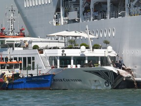 Rescuers stand onboard the damaged River Countess tourist boat after it was hit early on June 2, 2019 by the MSC Opera cruise ship (Rear) that lost control as it was coming in to dock in Venice, Italy. ANDREA PATTARO/AFP/Getty Images