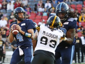 As Argonauts quarterback McLeod Bethel-Thompson (left) looks to throw the ball downfield, offensive lineman Randy Richards blocks out Connor McGough of the Tiger-Cats during last Saturday’s season opener for the Boatmen at BMO Field.  The O-line gets a major boost for Monday’s game in Regina when veteran all-star guard Ryan Bomben returns after missing the opener hurt. Jack Boland/Toronto Sun