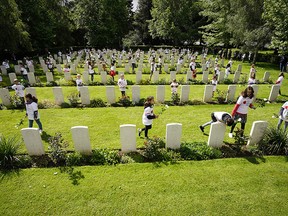 School children from the Normandy village of Cambes-en Plaine lay flowers at the graves of all the fallen in the village's British Military Cemetery during a remembrance service in the village on June 08, 2019 in Caen, France. (Photo by Christopher Furlong/Getty Images)
