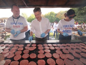 Ontario MPP Rob Phillips (Middle) helps flip burgers as Ontario Premier Doug Ford moved his annual Ford Fest BBQ north to Vaughan and entertained close to 5,000 Ford followers on Saturday, Sept. 22, 2018. (Jack Boland/Toronto Sun/Postmedia Network)