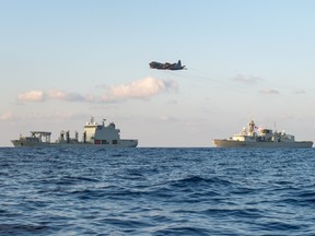 A CP-140 Aurora aircraft flies by the HMCS Regina (R)  and Naval Replenishment Unit ASTERIX (L) during Operation ARTEMIS on March 31, 2019. (Master Cpl.  PJ Letourneau, Canadian Forces Combat Camera)