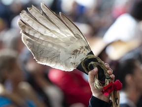 A red ribbon attached to an eagle feather is held up during ceremonies marking the release of the Missing and Murdered Indigenous Women report in Gatineau, Monday June 3, 2019. THE CANADIAN PRESS/Adrian Wyld