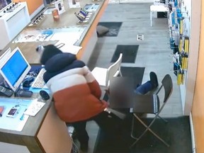 One of two unidentified bandits who robbed a cellphone store near Lawrence Ave. W. and Allen Rd. on Feb. 11 is seen on video beating a woman, 83, with a metal baton and and dragging the customer by her arm to a back room. (supplied by Toronto Police)