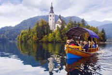 Visitors enjoy a scenic ride to a Lake Bled island on a traditional pletna boat. (Cameron Hewitt)