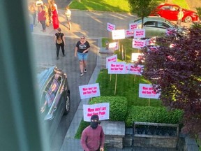 Upset protesters hold signs outside Hamilton's mayor that read "Mayor doesn't care about Queer People."