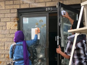 Members of the Owen Sound Muslim Association clean mustard off the front door of their mosque on Saturday, July 13, 2019 after it was vandalized for the second night in a row. (Supplied photo)