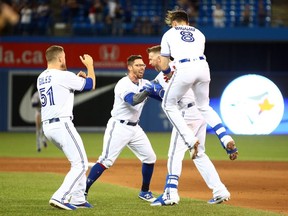 Ken Giles #51, Eric Sogard #5 and Cavan Biggio #8 of the Toronto Blue Jays celebrate with Justin Smoak #14 after he hit a game winning RBI single in the tenth inning during a MLB game against the Cleveland Indians at Rogers Centre on July 23, 2019 in Toronto.  (Photo by Vaughn Ridley/Getty Images)