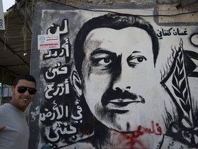 A Palestinian refugee stands next to graffiti depicting Palestinian writer Ghassan Kanafani with Arabic that reads his name and "I will not renounce before planting my paradise on earth," while marking "Nakba" or Catastrophe day in the West Bank city of Bethlehem, Sunday, May 15, 2016. Palestinians marked the 68th anniversary of their displacement following the Israeli declaration of independence in 1948. (AP Photo/Nasser Nasser)