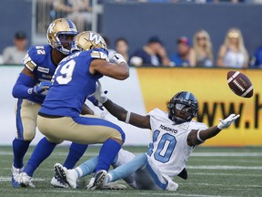 Winnipeg Blue Bombers' Kyrie Wilson (19) and Chandler Fenner (22) apply pressure as Toronto Argonauts' Armanti Edwards (10) can't hang on to the pass during first half CFL football action in Winnipeg, Friday, July 12, 2019. THE CANADIAN PRESS/John Woods