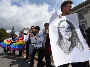 Activists of Ukrainian LGBT community hold a LGBT flag, signs reading " Stop Russian world" "stop hate" and pictures of Elena Grigorieva in front of the Russian embassy in Kiev on July 24, 2019. (Sergei SUPINSKY / AFP)