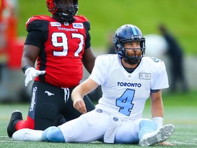 Beleaguered Argonauts quarterback McLeod Bethel-Thompson watches where his pass wound up after being knocked down by Stampeders’ Derek Wiggan on Thursday night in Calgary. Chances are it was picked off.   Al Charest/Postmedia