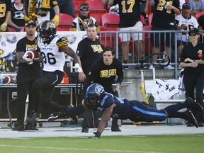 Tiger-Cats’ Bralon Addison (left) scampers past a diving Argonauts’ Justin Herdman-Reed.  Jack Boland/Toronto Sun