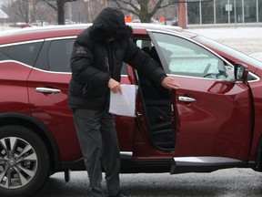 Claude Eric Trachy hides his face arriving at court in Chatham, Ont. on Friday April 6, 2018.