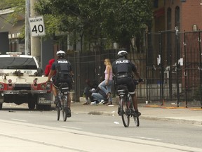 Toronto Police officers ride by a safe injection overdose prevention site on Dundas St. E., just east of Sherbourne Ave., on Saturday, July 27, 2019.
